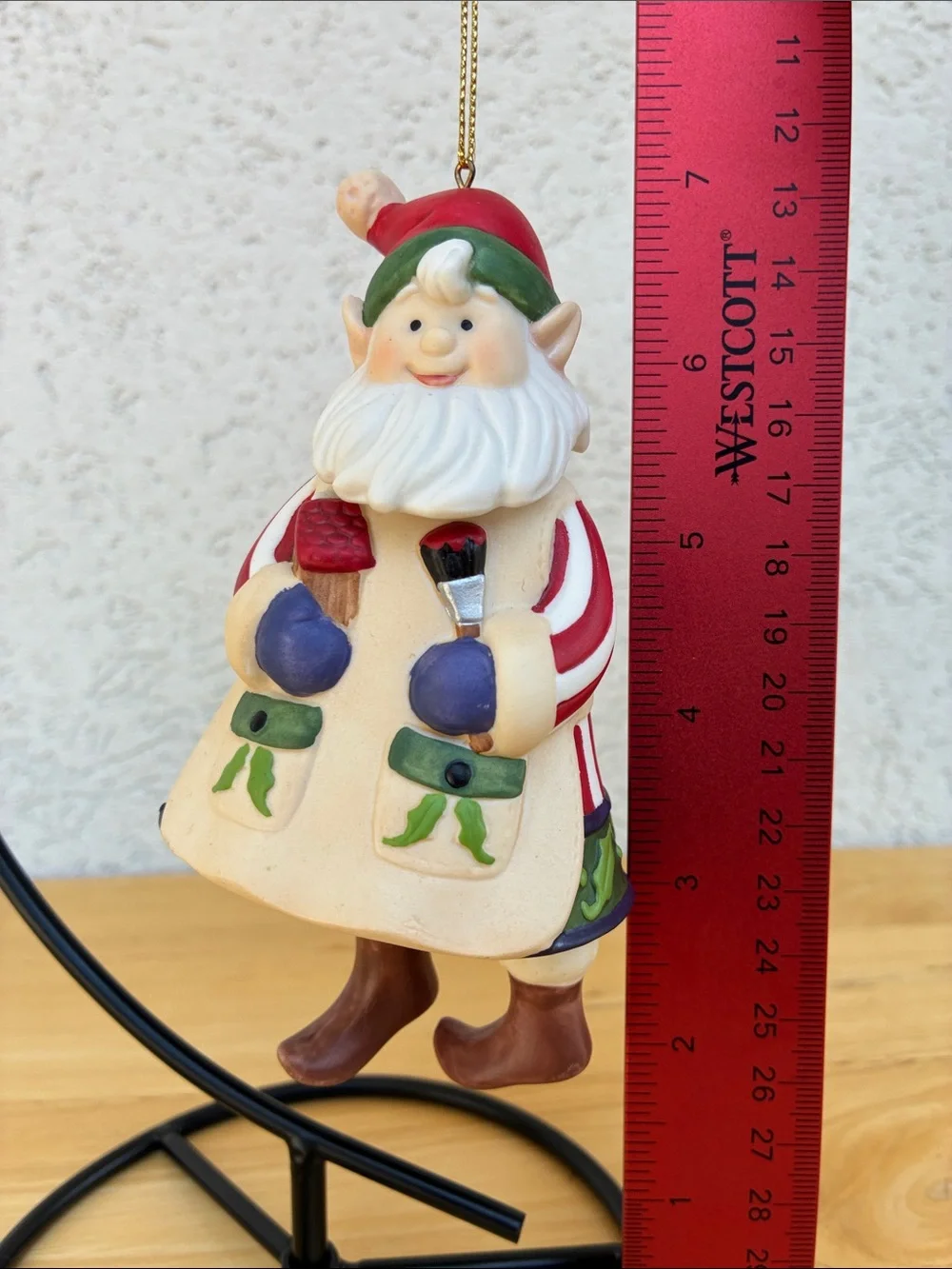Ceramic elf painting a bird house bell ornament with little floppy legs